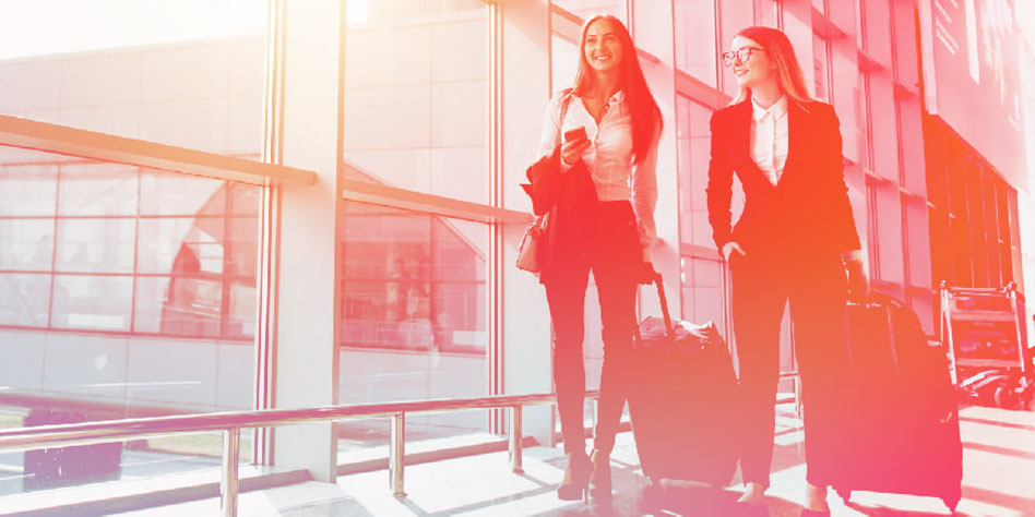 Two women traveling, wearing business dress.