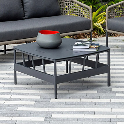 black outdoor coffee table decorated and place on a modern, paved deck