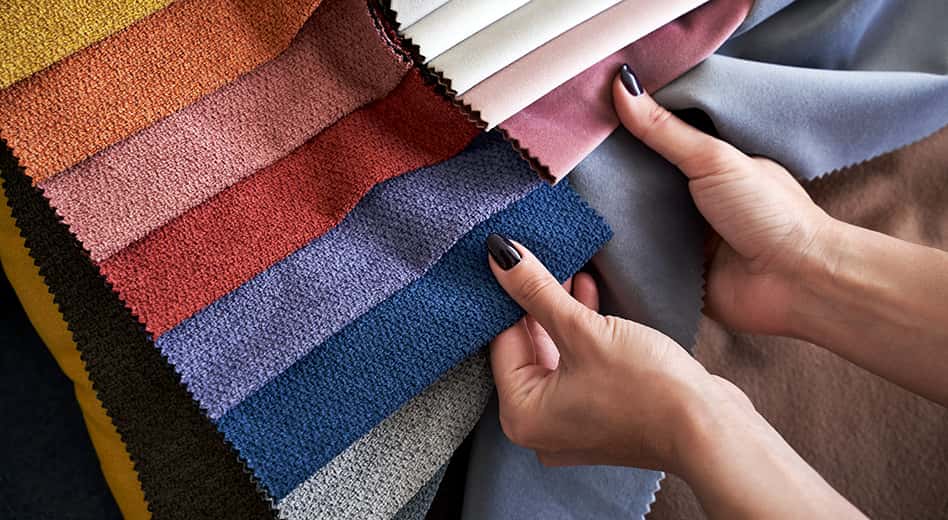 a close-up of hands holding and comparing fabric swatches and textures