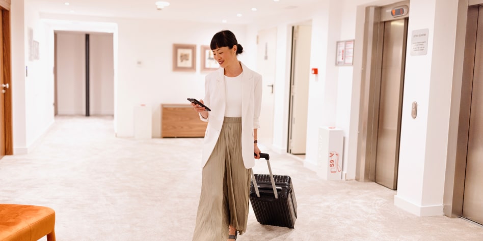 Refined woman traveler pulling suitcase down luxurious hotel corridor