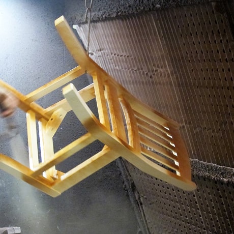 A wooden chair frame in the early stages of being stained