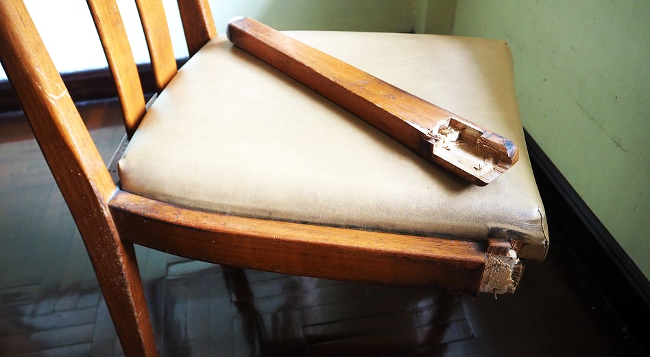 A wooden restaurant chair with a broken joint