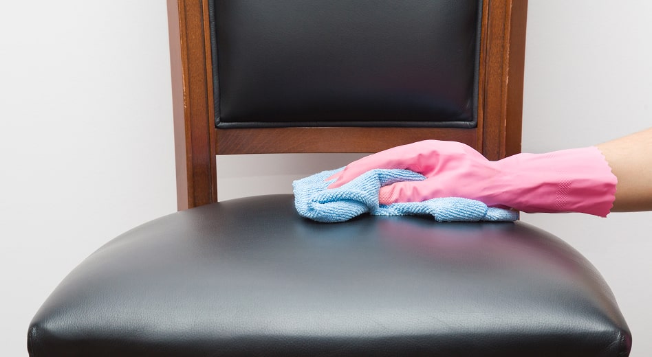 A hand wiping a vinyl chair cushion with a cloth